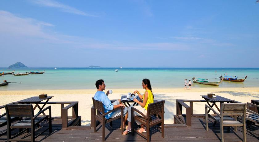 three people sitting on a wooden bench near the ocean, Phi Phi Holiday Resort (SHA Extra Plus) in Ko Phi Phi