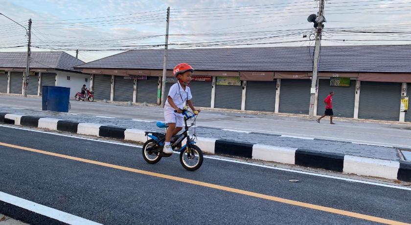a young boy riding a scooter on a city street, Chuanchom Resort in Phatthalung