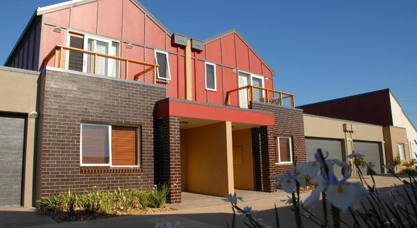 a brick building with a red door and windows, The Lakes Apartments in Lakes Entrance