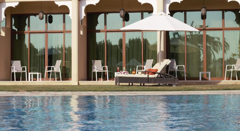 a patio area with chairs and umbrellas in front of a pool, Western Hotel - Madinat Zayed  in Madinat Zayid