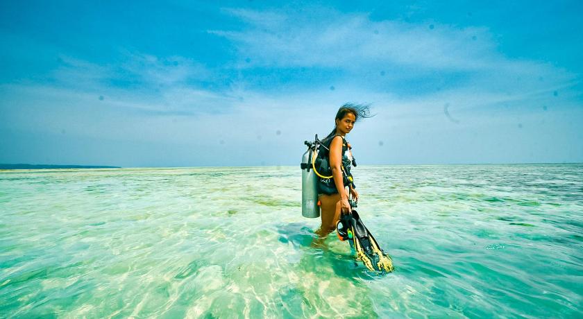 a woman standing on a beach holding a surfboard, Munjoh Ocean Resort - Havelock Island in Andaman and Nicobar Islands