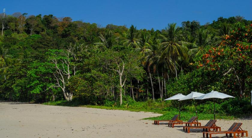 a picnic table with chairs and umbrellas on a beach, La Laanta Hideaway Resort in Koh Lanta