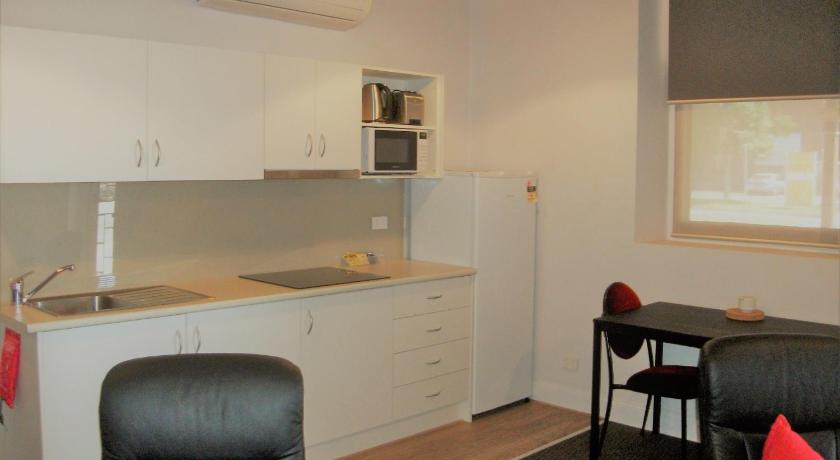 a kitchen with a table and chairs and a refrigerator, Daydream Motel and Apartments in Broken Hill