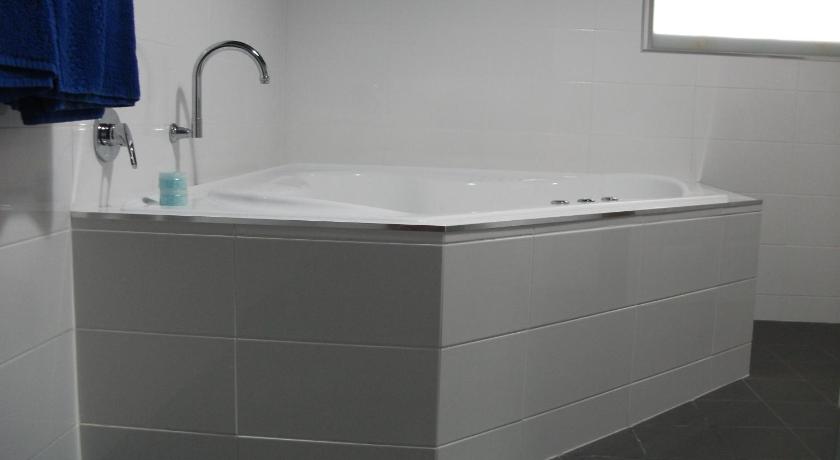 a white bath tub sitting next to a white sink, Daydream Motel and Apartments in Broken Hill