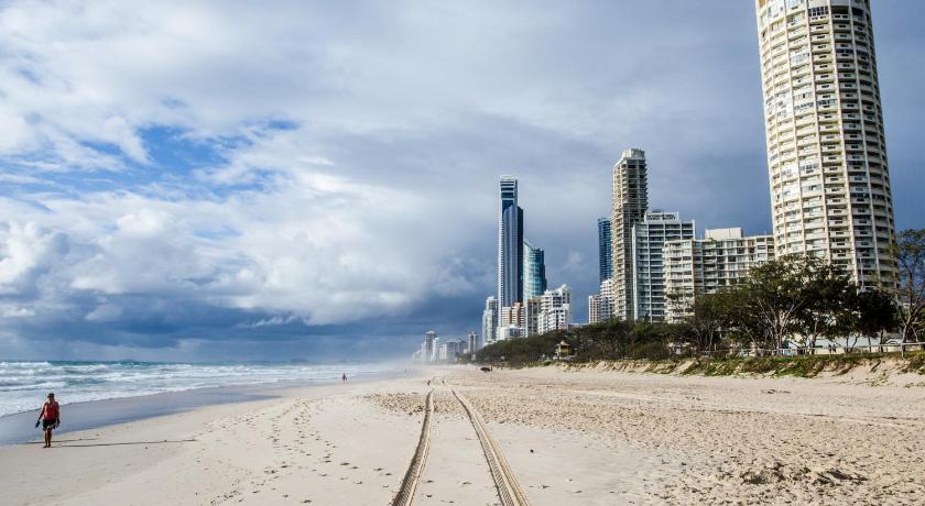 a person walking on a beach next to a body of water, The Shore Beachfront Apartments in Gold Coast