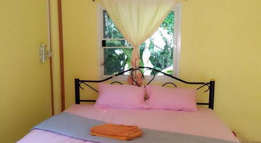 a bed with a pink and white bedspread and pillows, Baan Ton-Khathin in Koh Kood
