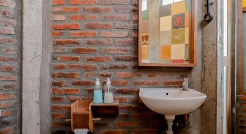 a bathroom with a sink, mirror and a brick wall, Lorong Homestay in Yogyakarta