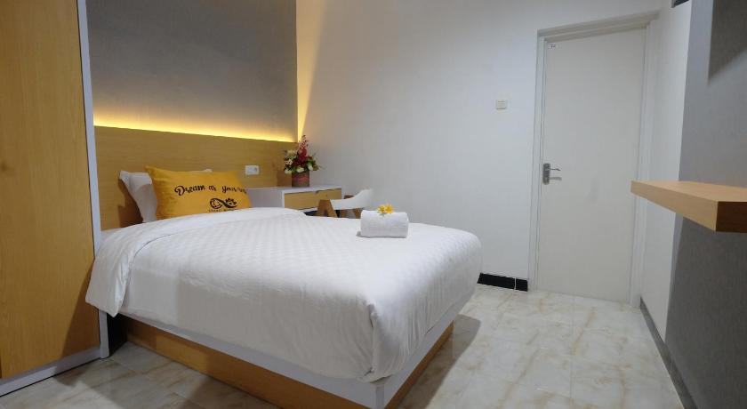 a hotel room with a bed, table, and dresser, Gapura Residence in Semarang