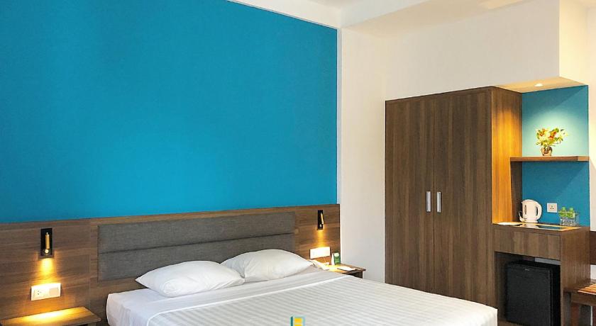 a bedroom with a white bed and a blue wall, Liberty Hotel Saigon Parkview in Ho Chi Minh City