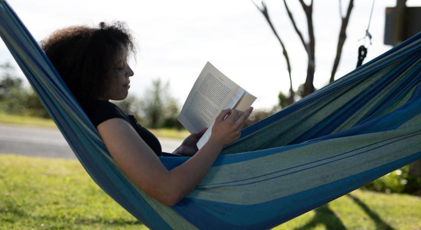 a woman is reading a book in the grass, Waiheke Backpackers Hostel in Waiheke Island