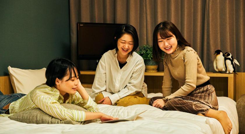 two women sitting on a bed next to each other, OMO7 Asahikawa by Hoshino Resorts in Asahikawa