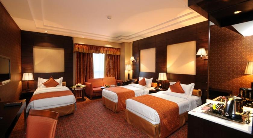 a hotel room with two beds and two tables, Rove Al Madinah Hotel in Medina