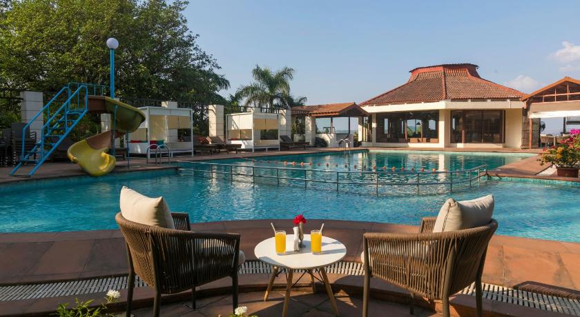 a dining room table with chairs and a pool, The Dukes Retreat Resort in Lonavala