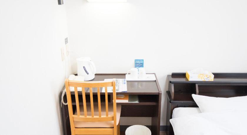a room with a bed, chair, desk and a lamp, Hikone Station Hotel in Hikone