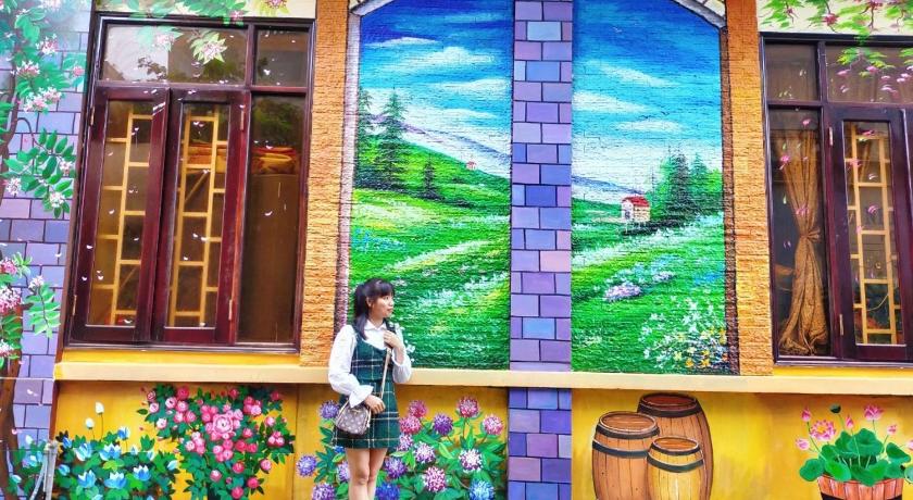 a woman standing in front of a mural painted on a wall, An Nhien Hotel. in Buon Ma Thuot