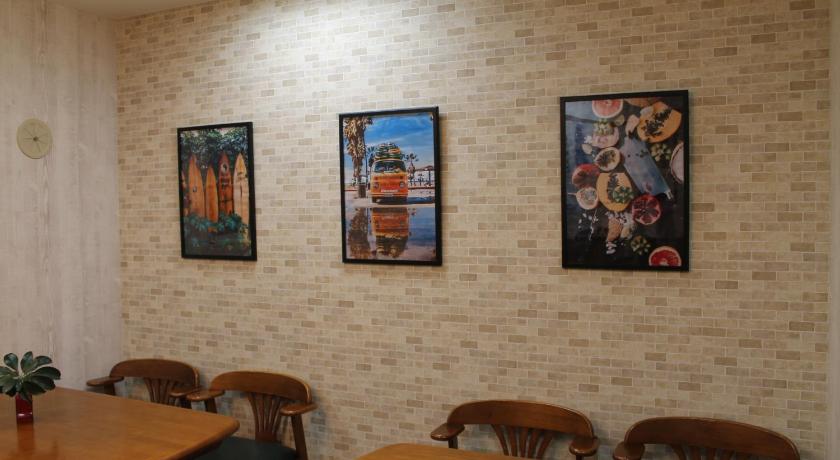 a room with a table and a wall with pictures on it, Okubo Hotel Hawaii in Tokyo