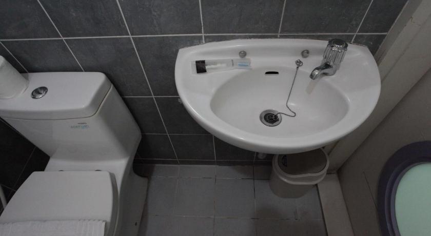a white toilet sitting next to a sink in a bathroom, LeGreen Suite Tebet in Jakarta