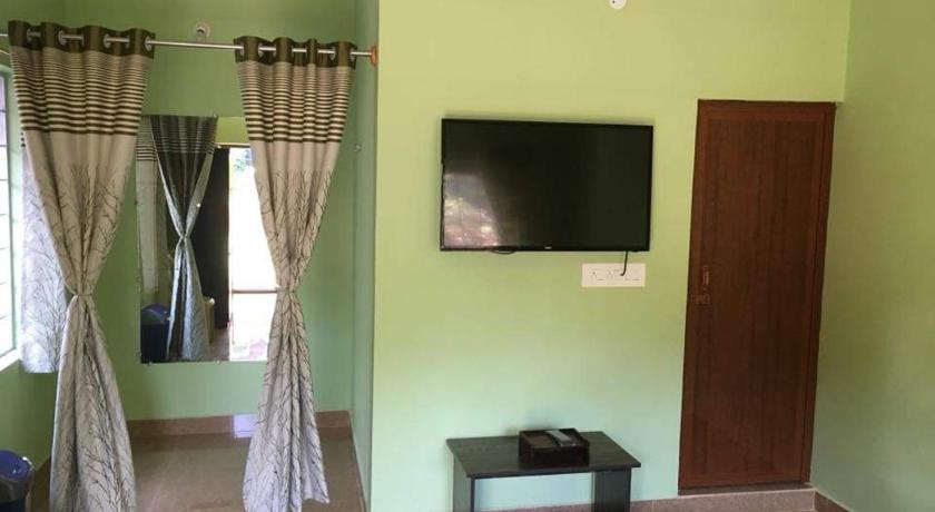 a room with a television and a rug, Nakshatra Guest house in Coorg