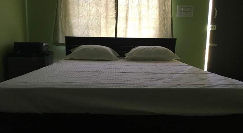 a bed with a white comforter and a window, Nakshatra Guest house in Coorg