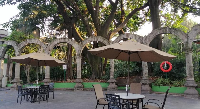 a patio area with tables, chairs and umbrellas, Holiday Inn Guadalajara Expo in Guadalajara