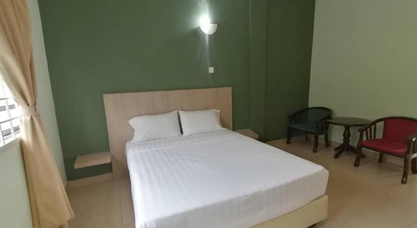 a bedroom with a bed, chair, and a lamp, S2 Hotel in Seremban