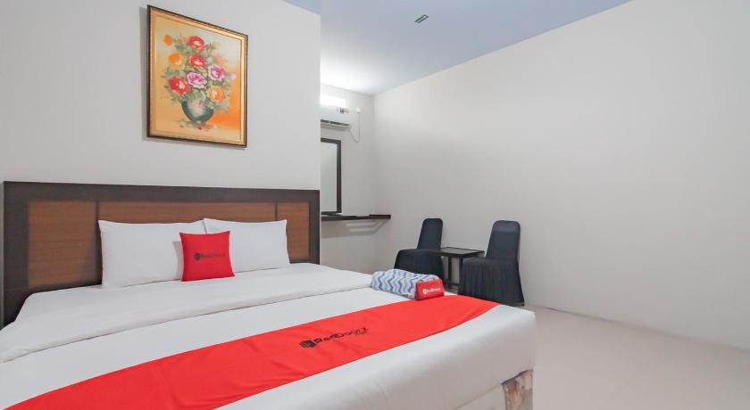 a hotel room with a bed, chair, and nightstand, RedDoorz Syariah near Stasiun Cianjur in Puncak