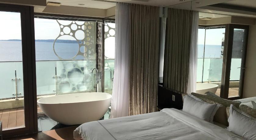 a hotel room with a large bed and a large window, Jeju Ocean Star Condominium in Jeju