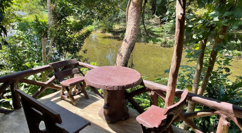 a picnic table with chairs and umbrellas in a wooded area, Art's Riverview Lodge in Khao Sok (Suratthani)