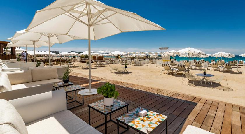 a patio area with chairs, tables and umbrellas, Carlton Cannes, A Regent Hotel in Cannes