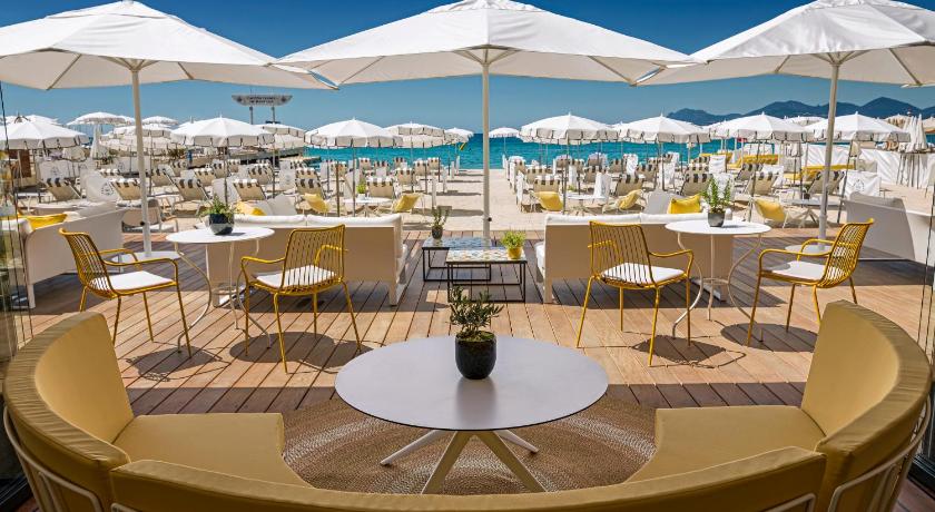 a patio area with tables, chairs and umbrellas, Carlton Cannes, a Regent Hotel in Cannes