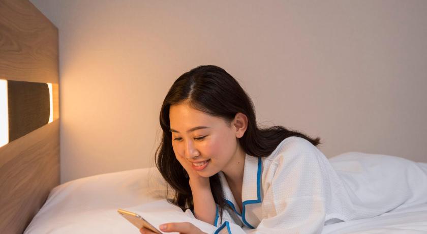 a woman sitting on a bed with a book, Comfort Inn Tokyo Roppongi in Tokyo