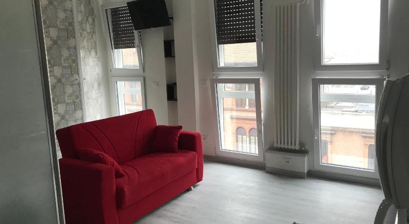 a red couch sitting in a living room next to a window, Itremoschettieri in Bologna