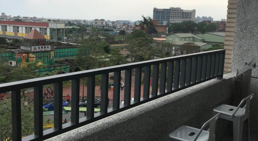 a patio area with chairs, tables, and a balcony, One Night Hostel in Yilan