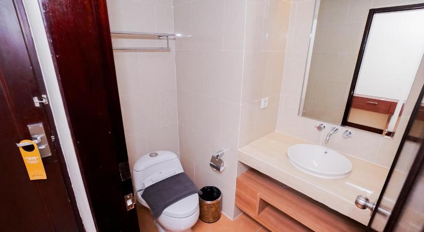 a bathroom with a toilet, sink, and mirror, Brits Hotel Pangkalan Bun in Pangkalanbuun