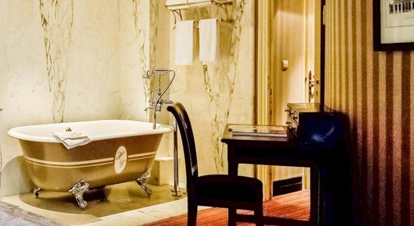 a bath room with a tub and a chair, Hotel du Romancier in Paris