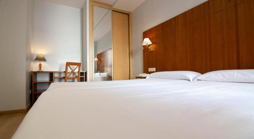 a hotel room with a bed and two lamps, Hotel Hispania in Zaragoza