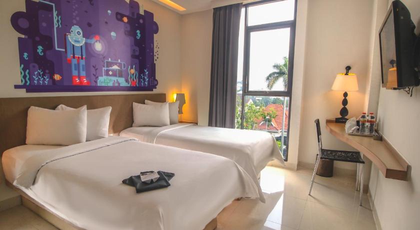 a bedroom with a bed, a chair, and a window, REGANTRIS Hotel Surabaya in Surabaya
