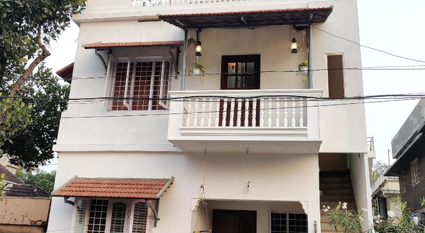a white house with a white balcony and a black dog on the balcony, Calvin's Inn in Kochi