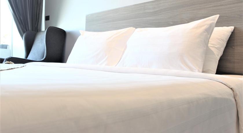 a bed with a white comforter and pillows, Mgrandhotel in Roi Et