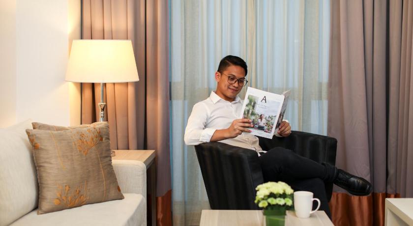 a man sitting on a couch reading a book, Citadines Uplands Kuching in Kuching
