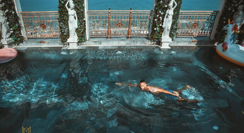 a man swimming in a pool next to a swimming pool, Monarque Hotel Danang in Da Nang