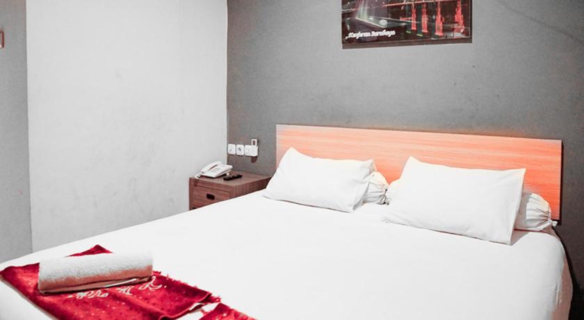 a hotel room with a bed and two lamps, Audah Syariah Residence RedPartner in Surabaya
