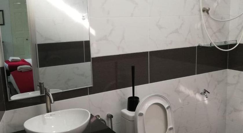 a bathroom with a toilet, sink, and mirror, RoomStay Hj Esmon Parit Raja UTHM in Batu Pahat