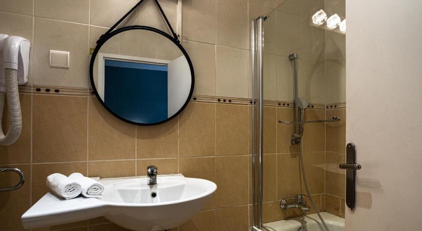 a bathroom with a sink, mirror, and shower stall, Azur Hotel in Marseille