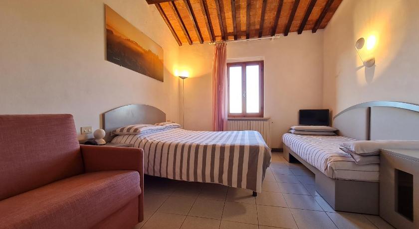 a living room with a couch, chair and a television, Hotel Da Graziano in San Gimignano