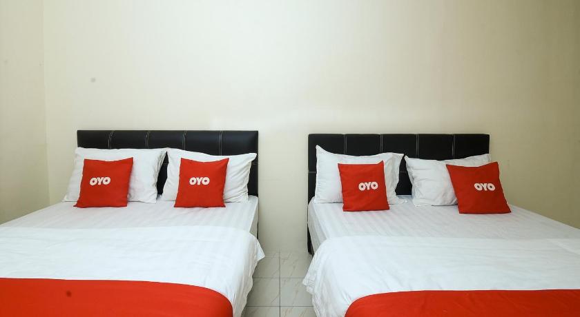two beds with white comforters and pillows in a room, OYO 90172 Batu Niah Homestay in Miri