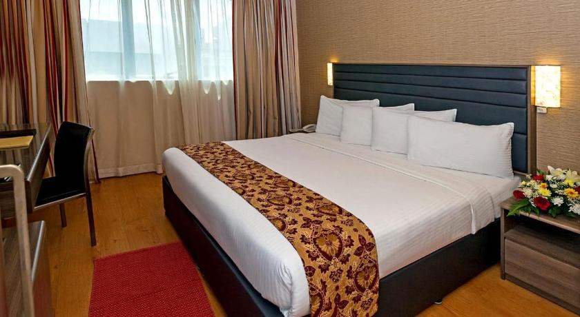 a hotel room with a bed, chair, and nightstand, Central Paris Hotel in Dubai
