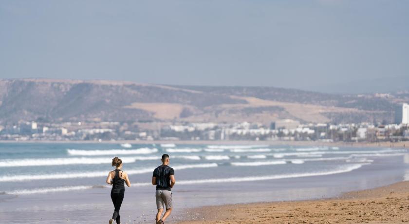two people walking on a beach near the ocean, Sofitel Agadir Thalassa Hotel in Agadir