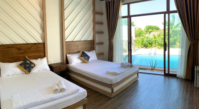a hotel room with two beds and a large window, Gia An Hung Guesthouse in Phan Thiet
