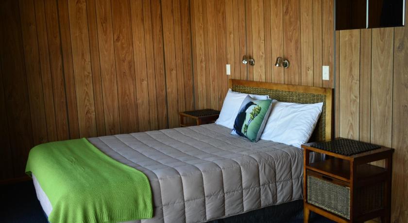 a bed in a room with a wooden headboard, Moeraki Beach Motels in Moeraki
